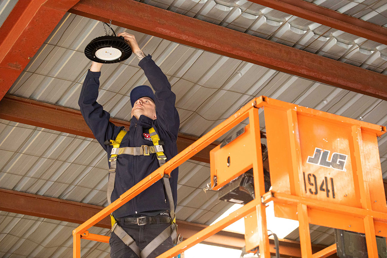 A proficient electrician working to perform industrial electrical work in a warehouse