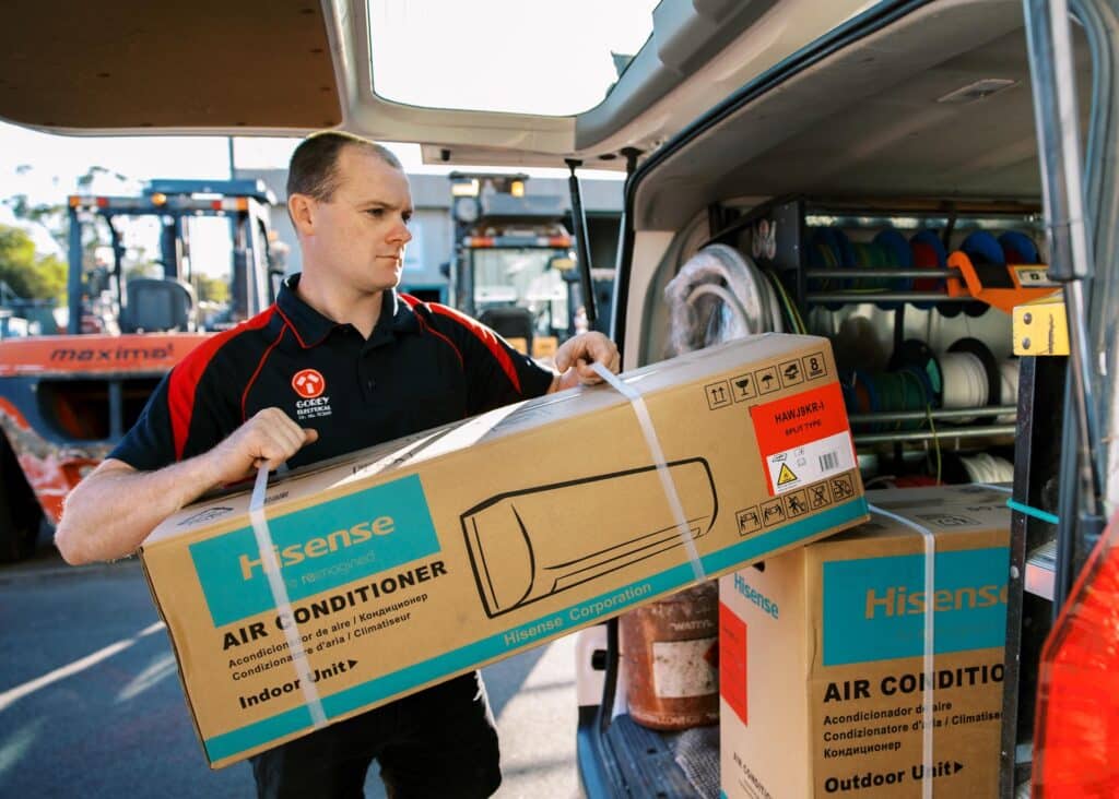 Electrician carrying an air conditioner unit